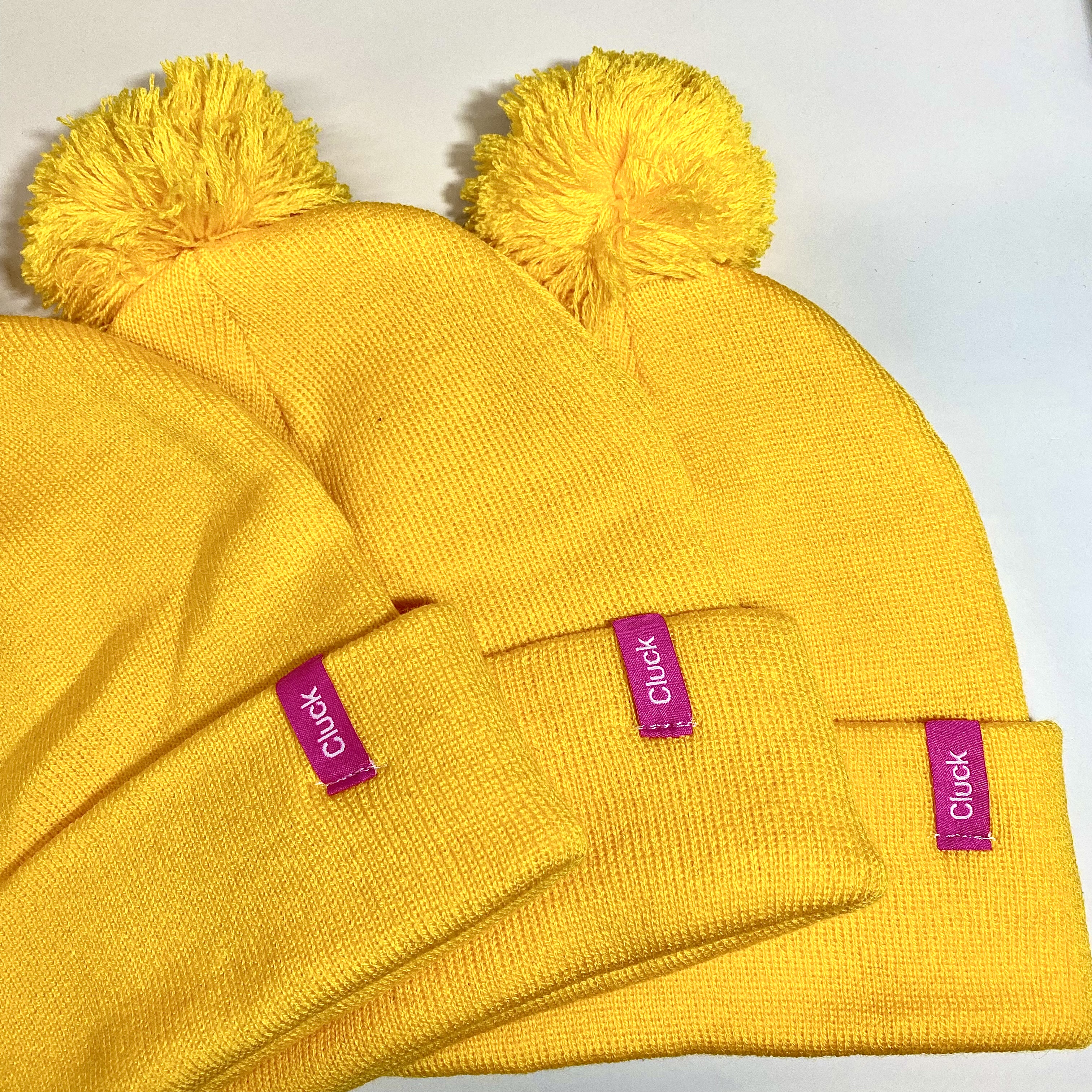 Cluck branded pom beanies with custom woven labels